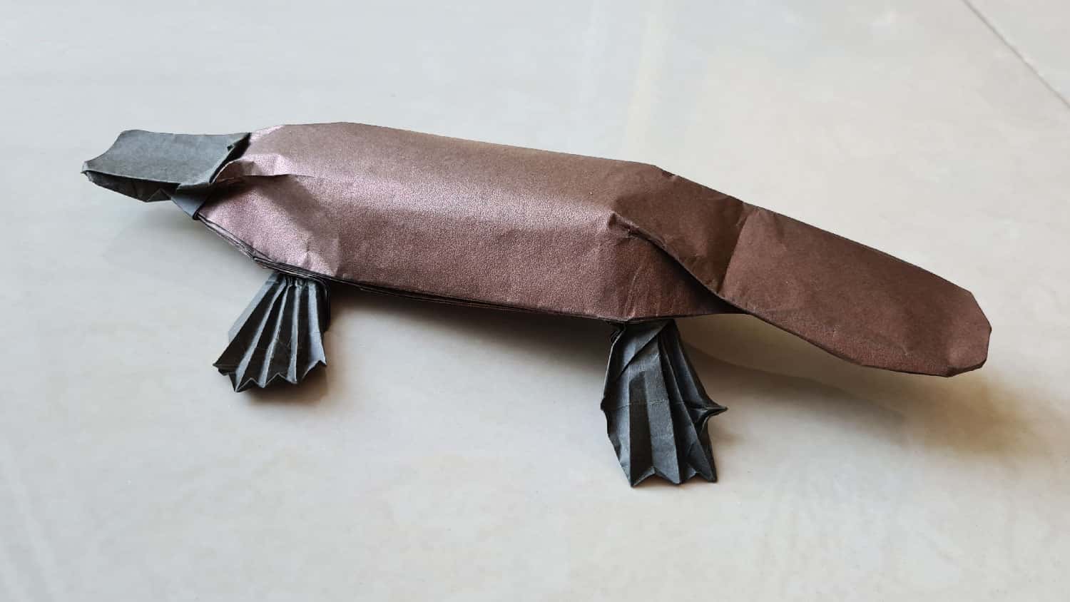 A folded origami platypus model, viewed from the side